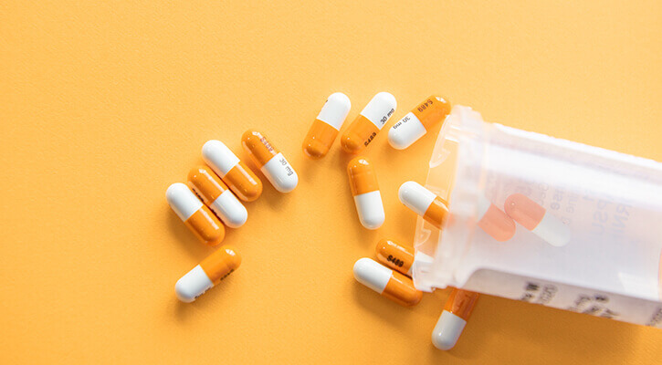 orange and white pills scattered across yellow backdrop